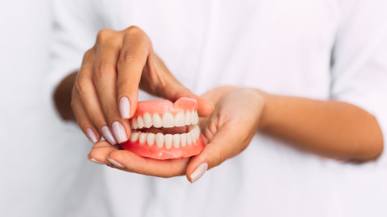 dentista segurando um modelo de prótese dentária removível 